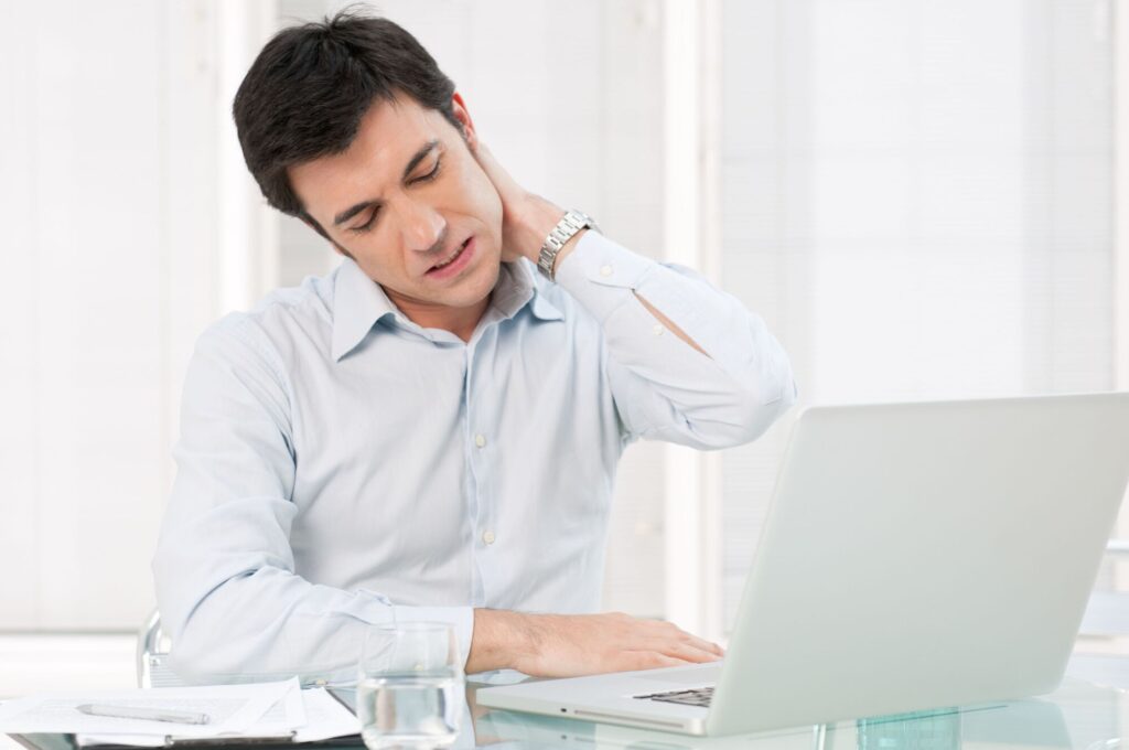 Male office worker experiencing neck pain from the effects of stress